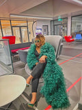 Person wearing a green ruffled coat in an office setting