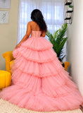 A woman viewed from behind wearing a voluminous pink tulle ball gown with a strapless corset-style bodice