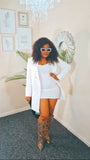 Woman in a white outfit with snake print boots standing in a room with decor elements.