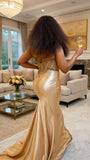 Woman in a gold evening gown holding a glass of champagne in a luxurious living room.