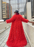 Person wearing a red ruffled coat on a rooftop with cityscape background