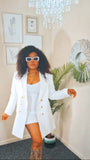 Woman in a white outfit with gold buttons standing in a room with decorative elements.
