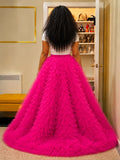Person wearing a bright pink tiered skirt in a room with shelves.